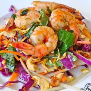 A tasty looking plate of boiled shrimp on top of a bed of salad.