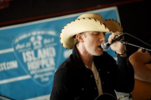 Image of a male songwriter singing into a microphone at the 2017 Island Hopper Songwriter Festival.