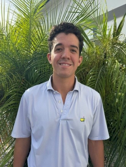 Portrait of a smiling man in a light polo shirt with tropical palm foliage in background